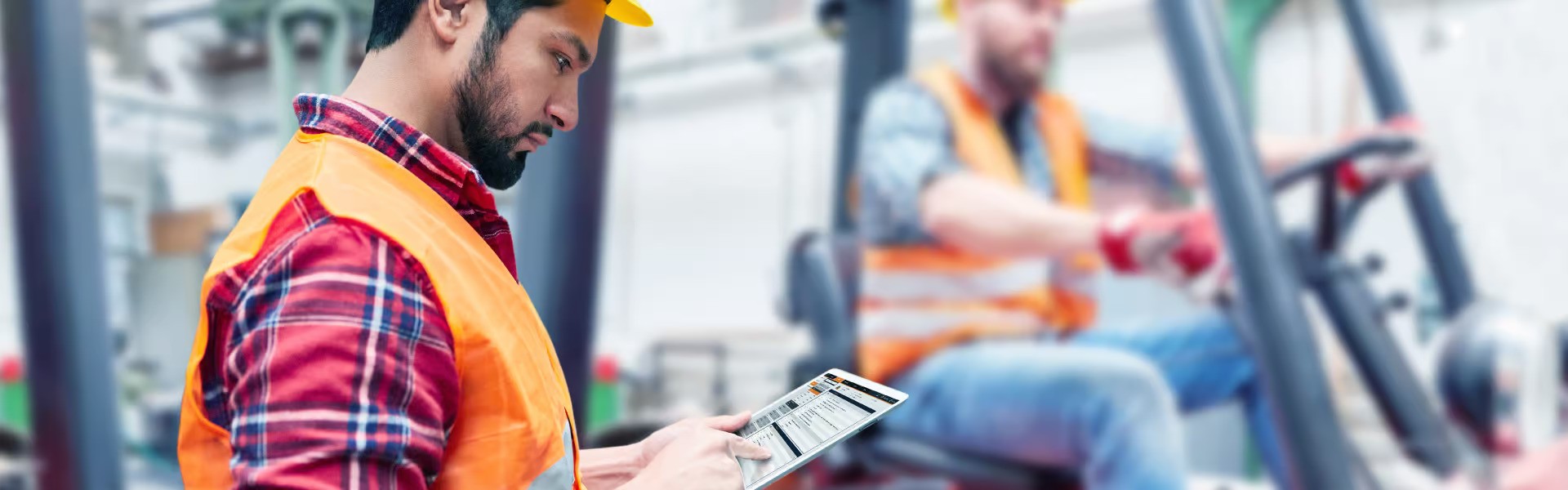 One worker operating forklift at the back and another worker in front using WorkX Connect