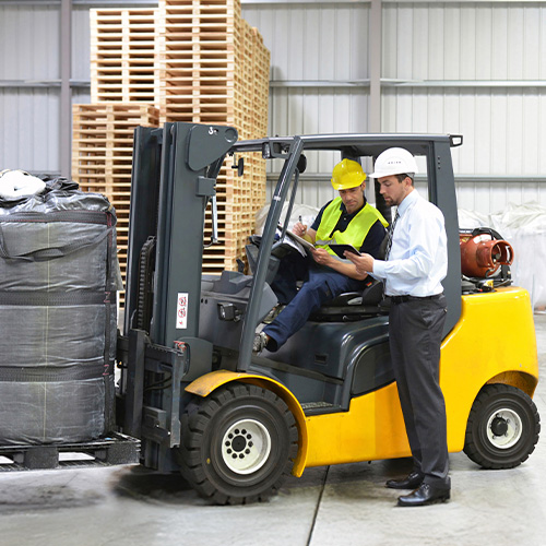 2 workers reviewing alert footage next to a forklift