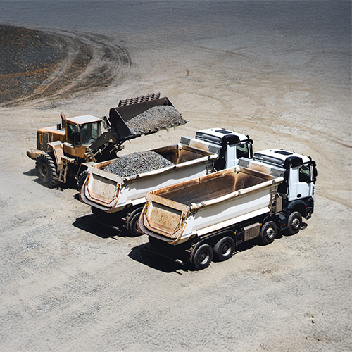 2 dump trucks and a loader