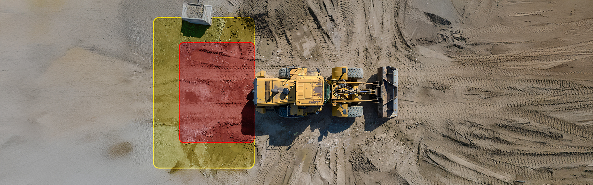 Loader driving down a dirt ride with a rear hazard detection zone.